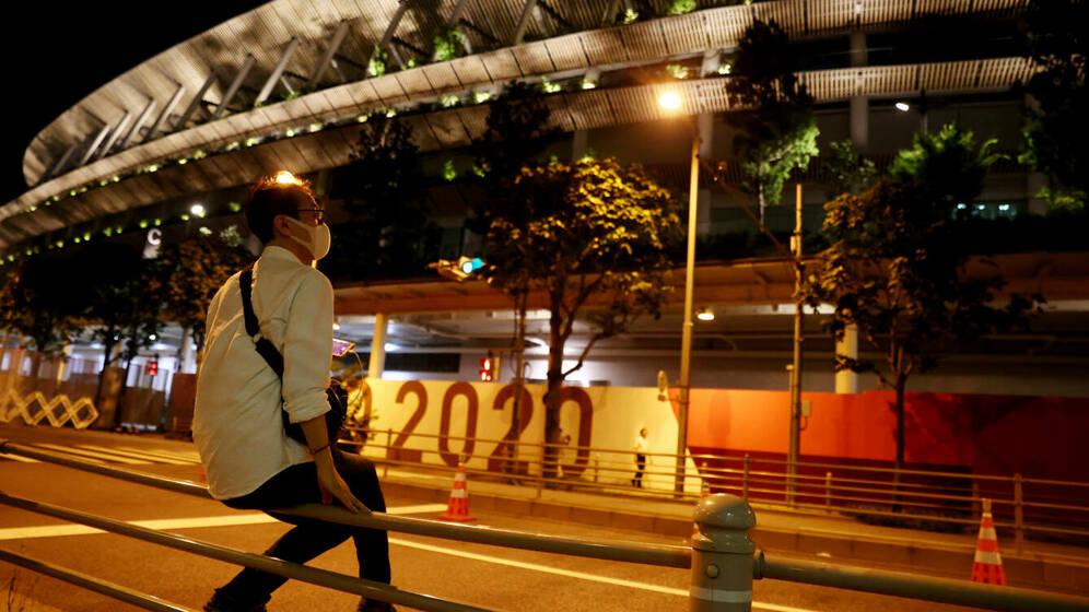 tokyo-2020-olympics-olympic-stadium-tokyo-japan-july-22-2021-a-man-wearing-a-mask-sits-outside-the-olympic-stadium-reuters-thomas-peter